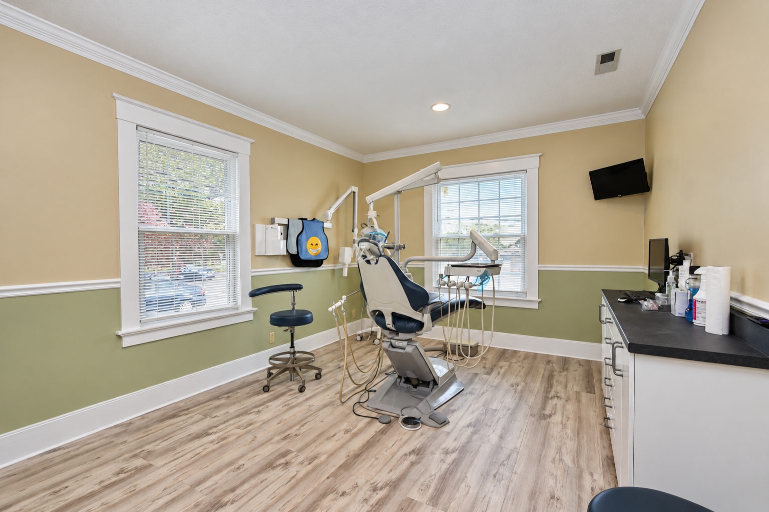 Treatment room with dental chair, delivery unit, wall-mounted x-ray and cabinetry